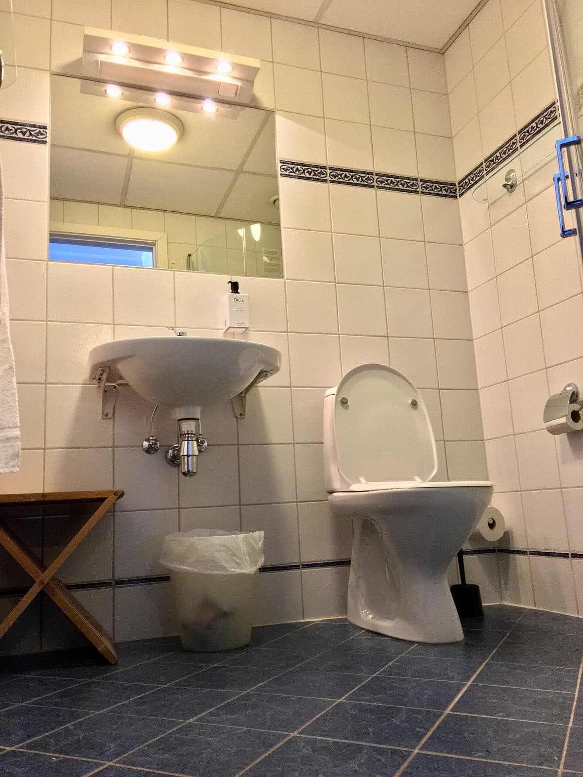 Hotel bathroom with basin, toilet, and a shower cubicle. Amenity reference, not an OPod.